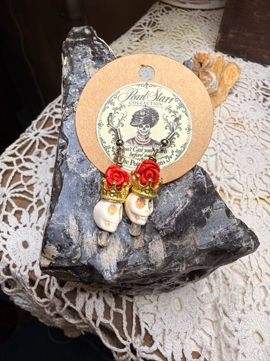 Pearl Starr earrings with red resin roses, gold-colored crowns, ivory-colored skull beads, and clear faceted drops.